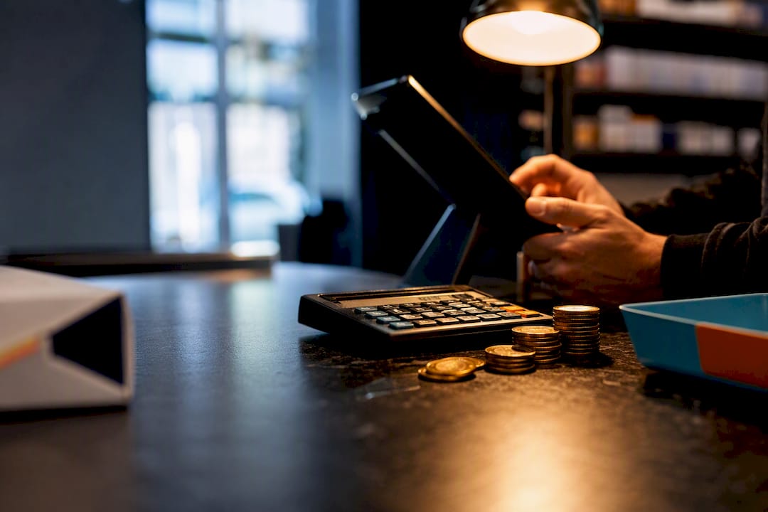 Calculator and coins beside anonymous cigarette pack edge
